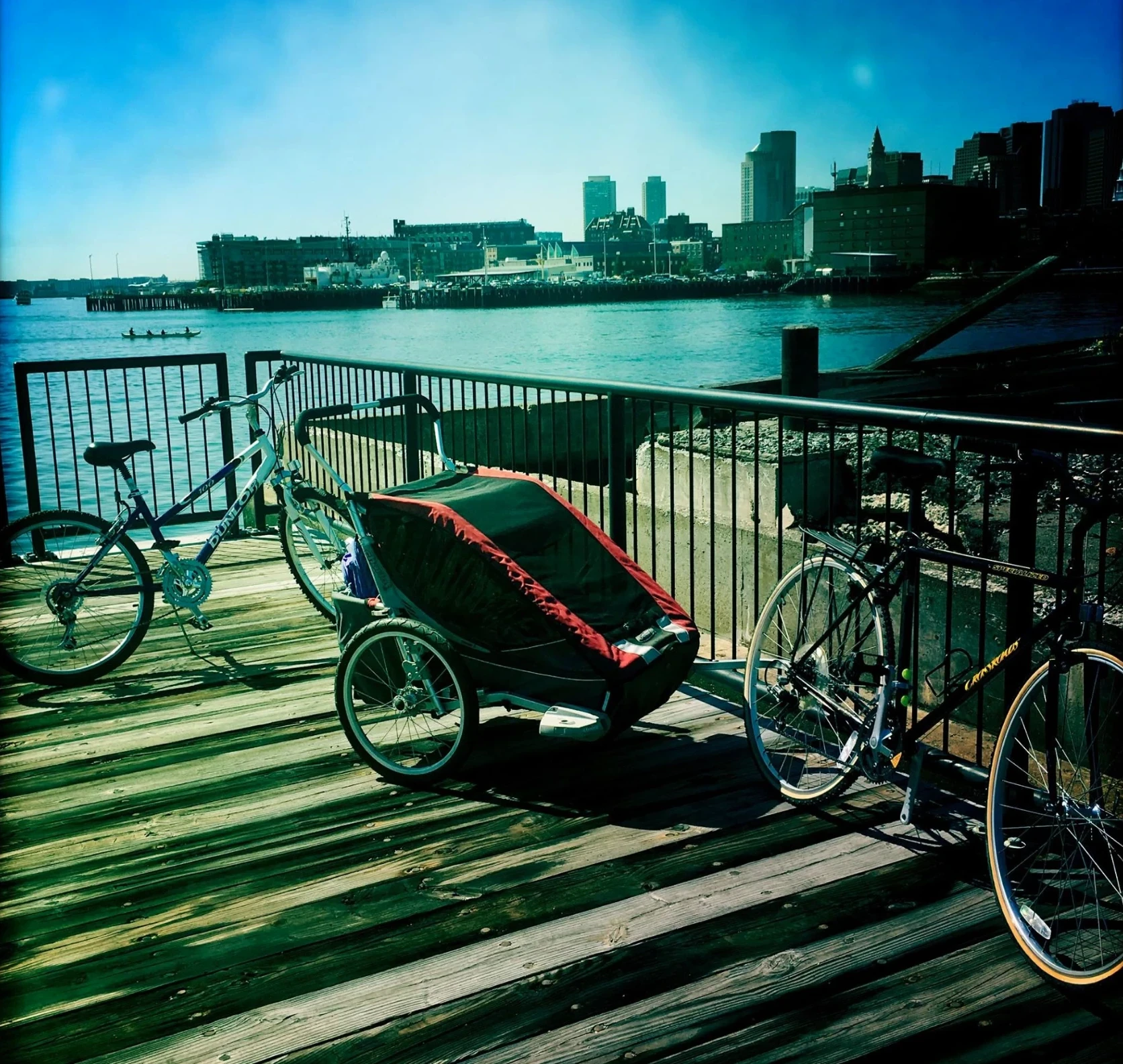 Bikes and a child trailer parked on a waterfront boardwalk in Boston
