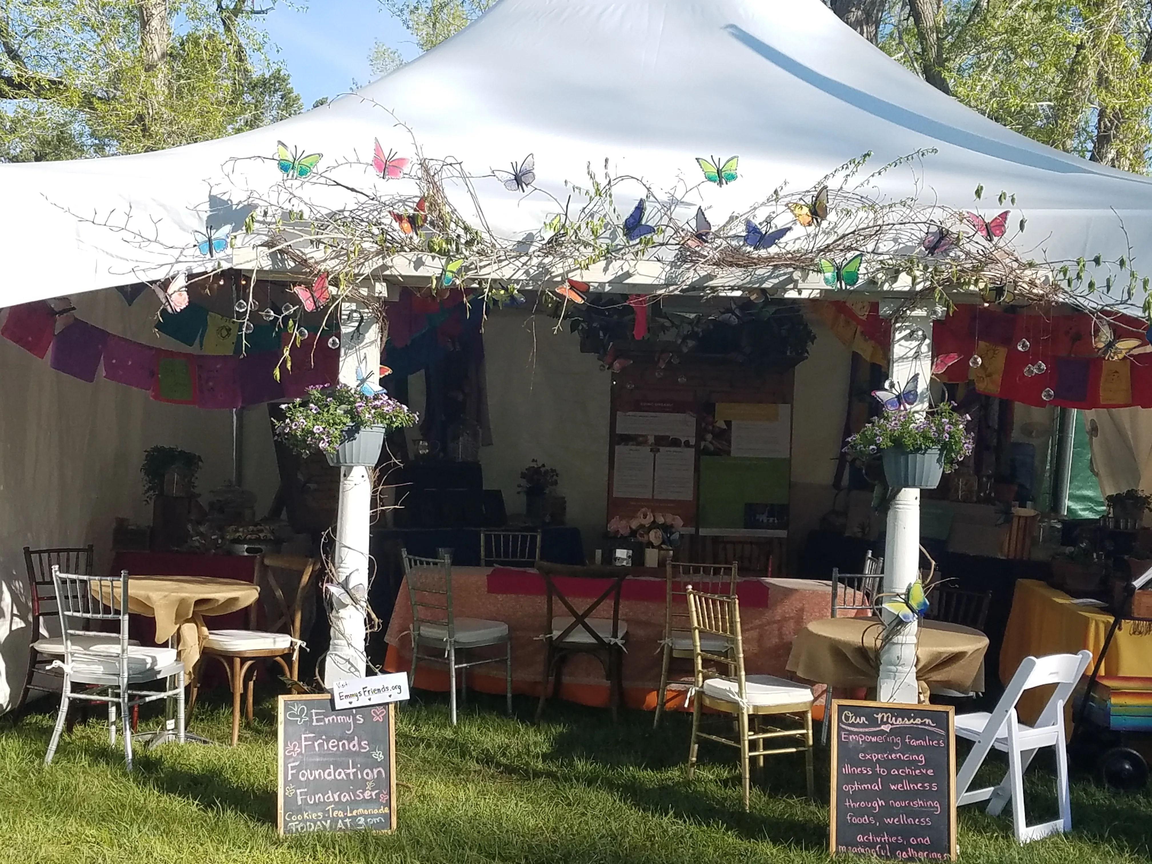 Emmy's Friends booth at Campout 2019 with butterflies, prayer flags, and mission chalkboards