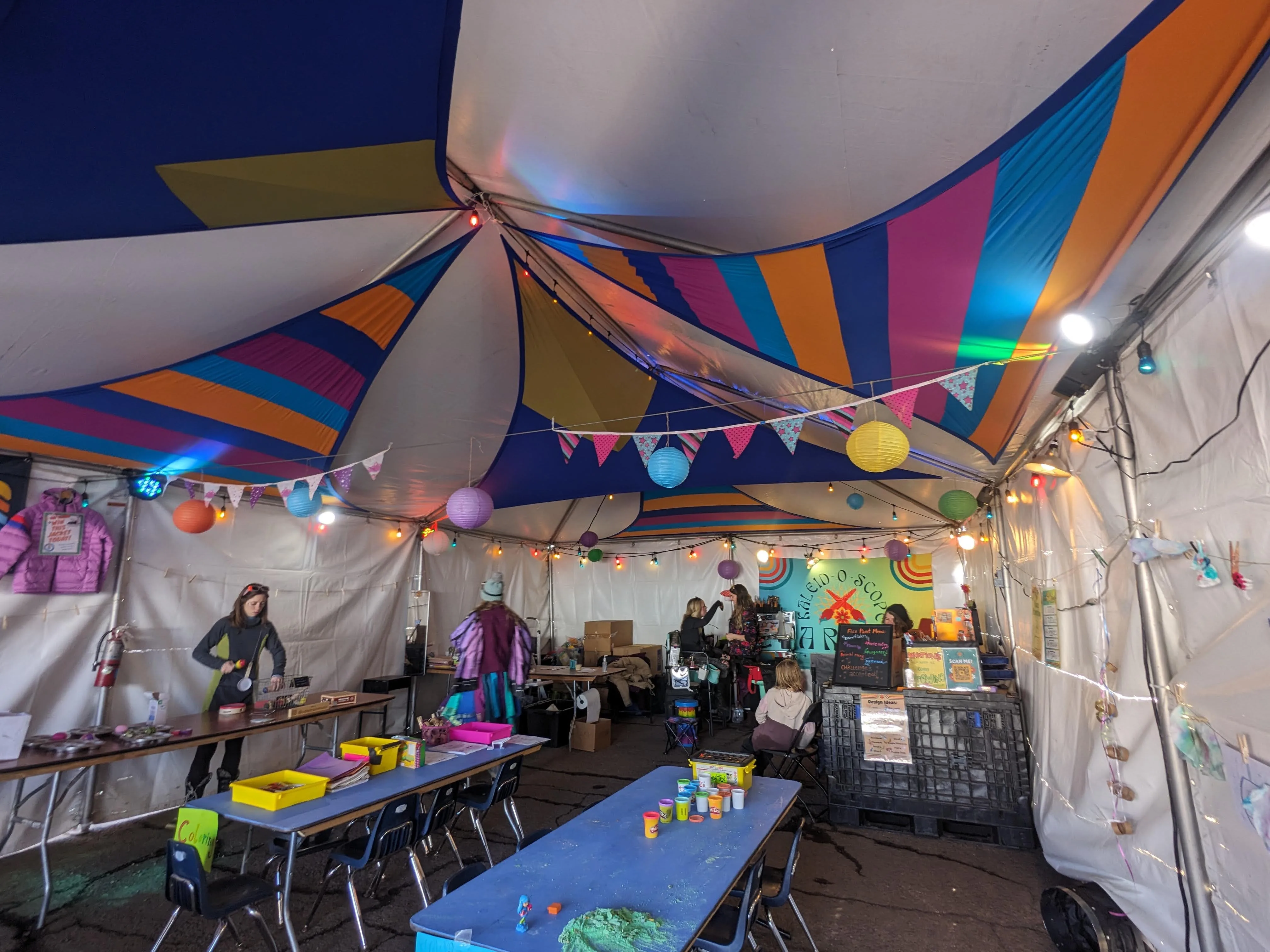Colorful kids zone tent with art tables, lanterns, and bunting