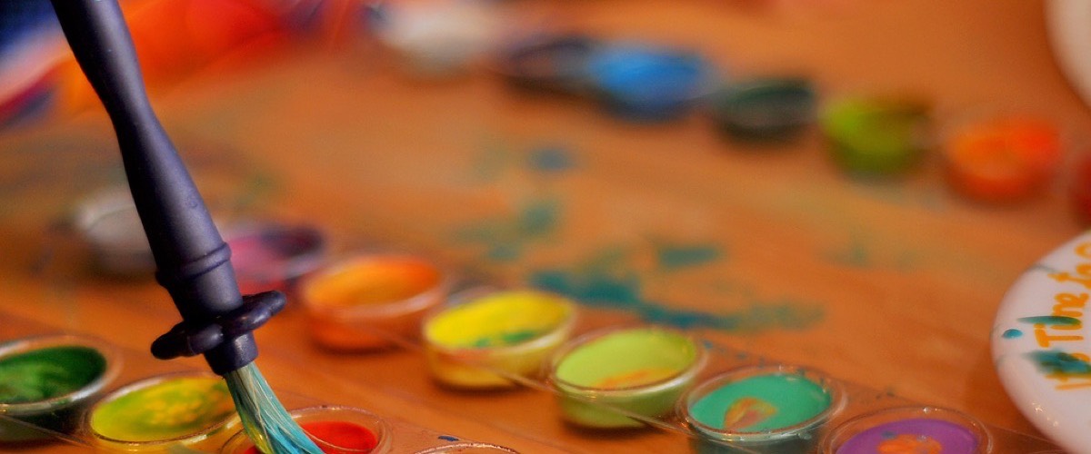 A watercolor paint palette and brush